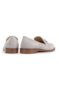 Mocassini in suede grigi con tacco di legno basso, caratterizzati da una patta decorativa sulla punta e linee pulite in un design classico.