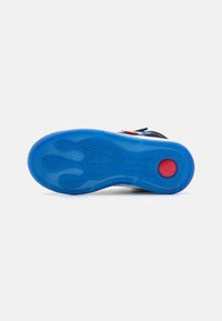 Suela de zapato con una suela de goma azul texturizada y un acento circular rojo, diseñada con ranuras ergonómicas para ofrecer tracción y agarre.