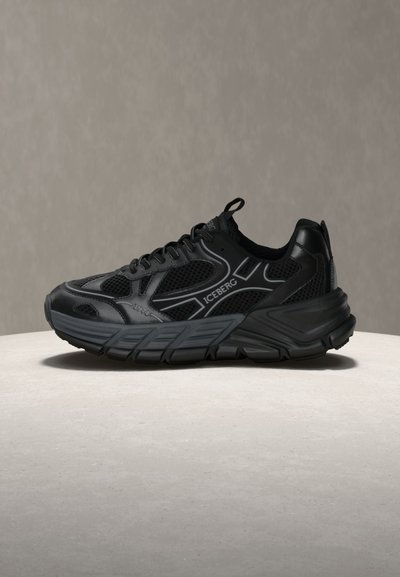 Μαύρο αθλητικό παπούτσι με πάνελ από δίχτυ, παχιά σόλα και το λογότυπο "ICEBERG" στο πλάι, τοποθετημένο σε φωτεινή επιφάνεια με απλό φόντο.