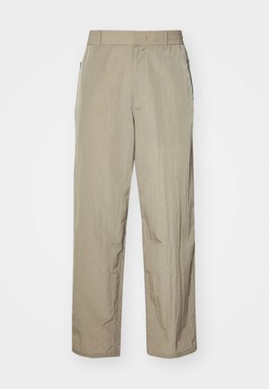Beige lätta byxor med avslappnad passform, som har resårmidja och sidofickor. Tyget verkar ha en textur och är lätt rynkat.