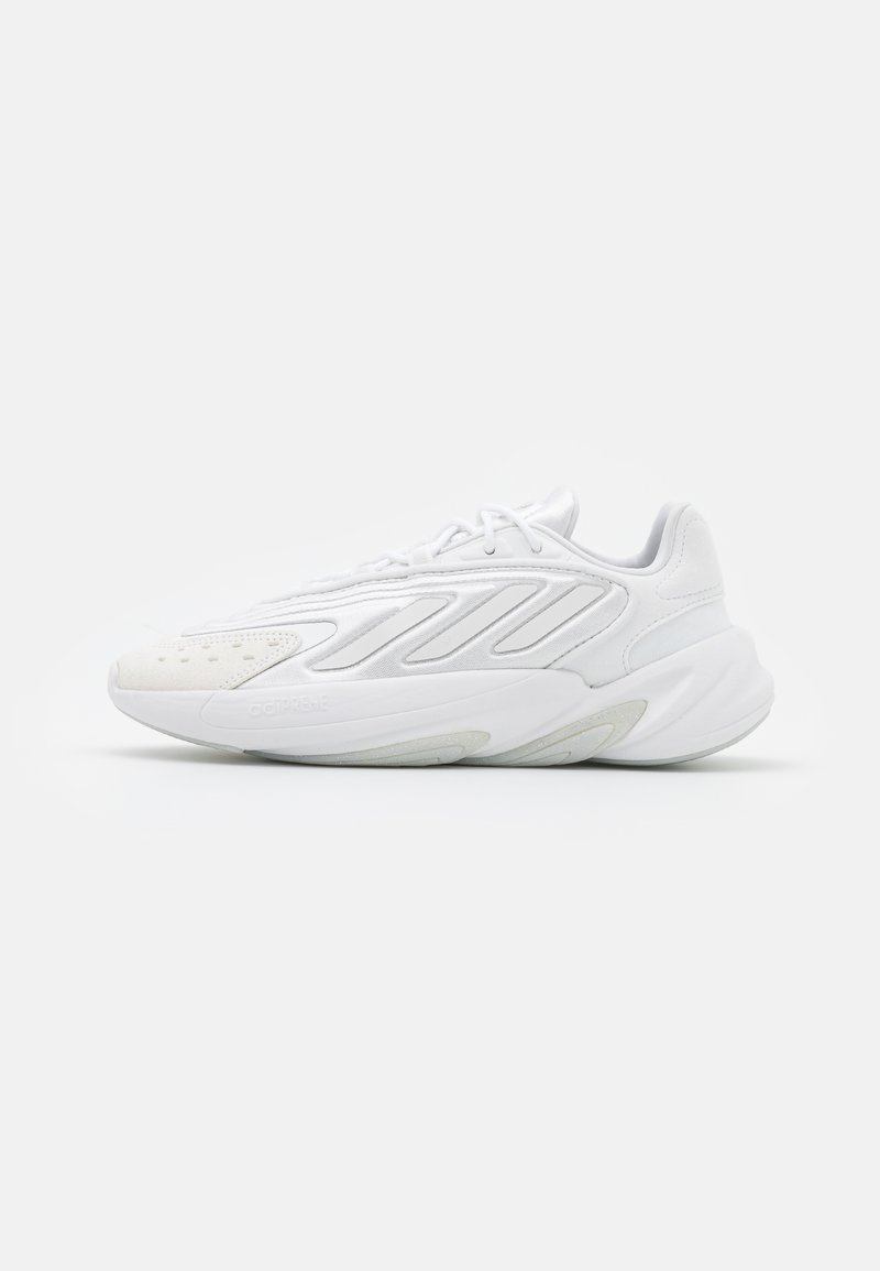 Białe sportowe sneakersy z teksturowanym wierzchem, zakrzywioną podeszwą i wydłużonym fasonem z bocznymi paskami oraz perforacjami na palcach.