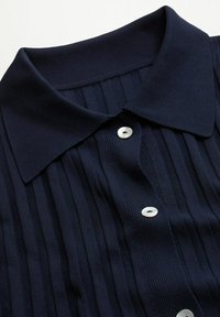 Navy blue collared shirt with a ribbed texture, featuring three white buttons and vertical pleats along the front for added detail.