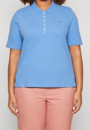 Sininen lyhythihainen poolopaita, jossa on klassinen kaulus, viiden napin nappilista ja pieni merkkilogo rinnassa. Pehmeä, sileä kangas.