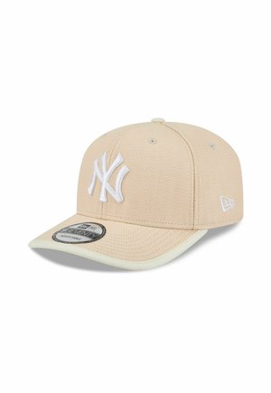 Beige New York Yankees adjustable baseball cap with white embroidered logo and contrasting brim edge, shown against white background.