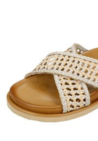 Sandalo intrecciato con design a strap incrociati, caratterizzato da una tomaia beige testurizzata, suola interna in morbida pelle color nocciola e suola in gomma di colore chiaro.