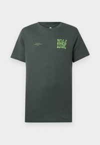 T-shirt de algodão verde escuro com mangas curtas. Frente apresenta grande logo "NIKE" em verde e texto menor, gola redonda clássica, textura lisa.
