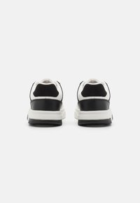 Pair of black and white sneakers shown from the back on a plain white background.