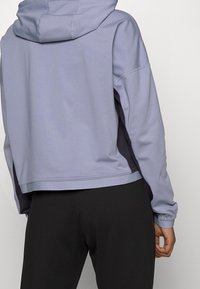 Lichtpaarse capuchontrui met een cropped design, zijpanelen in donkergrijs en elastische manchetten, met een gladde, zachte textuur.