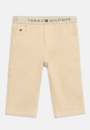 Bež hlače za malčke z elastičnim pasom, na katerem je napis "Tommy Hilfiger" in logotip, ter majhen logotip na sprednjem levem žepu.