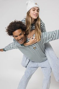 Stripet langermet skjorte i grønn og hvit, med rund hals og brodert logo. Kombinert med lyseblå jeans og en strikket lue.