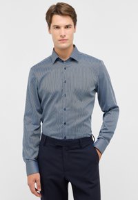 Blauw gestreept overhemden met een knoopsluiting aan de voorkant, een gespreide kraag, lange mouwen en contrasterende donkere knopen, gecombineerd met donkere broeken.