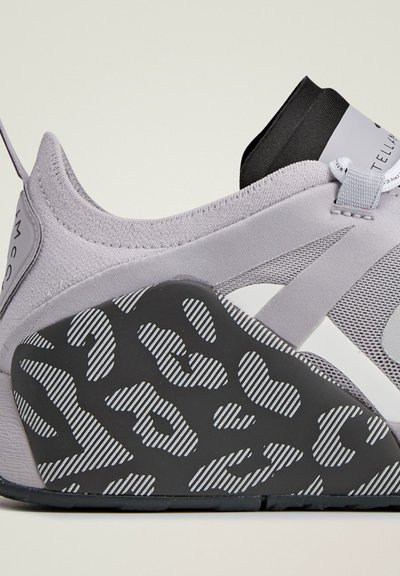 Gray athletic shoe with mesh upper, rubber sole featuring a black and white striped leopard print pattern, and elastic strap detail.