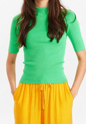 Groen geribd gebreid topje met een hoge hals en korte mouwen, gecombineerd met gele geplooide broek. De stof heeft een gestructureerd en aansluitend ontwerp.