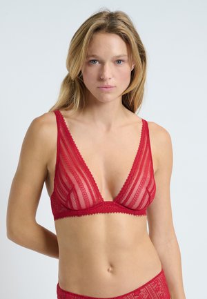 Bralette en dentelle rouge avec un décolleté en V profond, des panneaux transparents, des bords festonnés et des bretelles réglables, présentant une texture douce et un design complexe.
