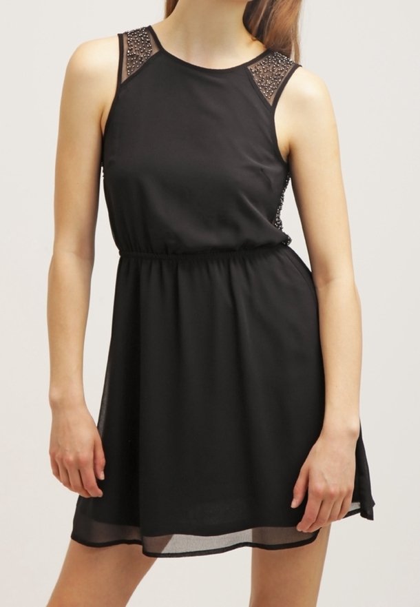 Černé bezramínkové šaty s těsným pasem, průhlednými síťovanými ramenními částmi zdobenými cvočky a splývavou sukní, která končí nad kolenem.