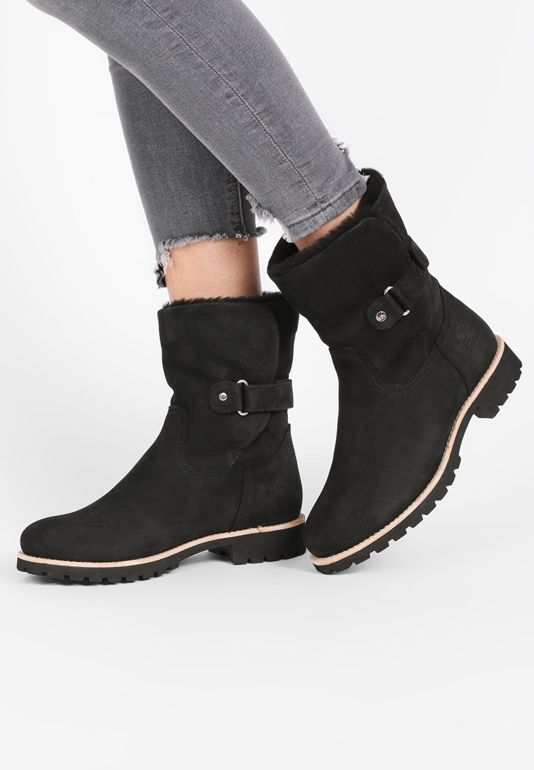Svarta mocka ankelstövlar med en vikad topp, spänne och texturerad sula. Har en ljusbeige yttersula för kontrast.