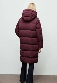 Abrigo acolchado burdeos con capucha, que presenta secciones acolchadas horizontales, mangas largas y un corte hasta la rodilla. Tela suave e insulated.