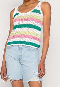 Top z koronkowym splotem, w paski w kolorach zielonym, różowym, białym i żółtym. Posiada falbaniasty dekolt. Połączony z jasnoniebieskimi, zniszczonymi szortami.