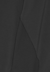 Närbild av mörk tyg med en slät sektion som överlappar ett strukturerat rutmönster, vilket visar kontrasterande material i svarta nyanser.