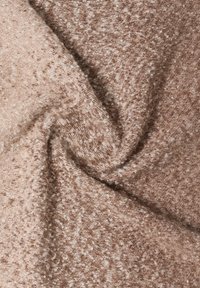 Vaaleanruskea neulottu kangas, jossa teksturoitu pinta ja täplikäs kuvio kermaan ja hentoon kiiltoon. Pehmeä, hieman joustava materiaali.