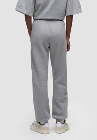 Grijze katoenen trainingsbroek met een elastische tailleband en opgerolde enkels, met een ontspannen pasvorm. Draag met witte sneakers.