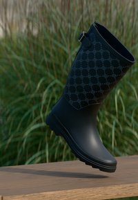 Botte de pluie en caoutchouc noir avec un motif texturé, une sangle ajustée et un bout rond. Convenable pour les conditions humides avec une semelle durable.