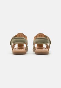 Sandaler med brun lærbase, grønne stofremme og Velcro-lukninger. Åben hældesign med flad sål. Glat tekstur.
