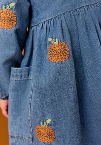 Denim jurk met oranje geborduurde pompoenen, gathered mouwen, een voorzak en een relaxte pasvorm met een zachte textuur.