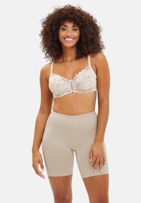 Bralette de encaje en beige con patrón floral y tirantes ajustables, combinado con pantalones cortos de cintura alta en beige claro, de textura suave.