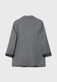 Blazer gris de rayas con cuello y mangas tres cuartos. Presenta puños de satén negro y corte recto. La tela tiene un acabado texturizado.