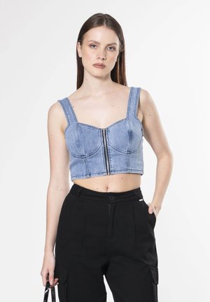 Korte denim top in lichtblauwe kleur, vierkante halslijn, brede schouderbanden, voorritssluiting en aansluitend ontwerp. Draag met hoge zwarte broeken.