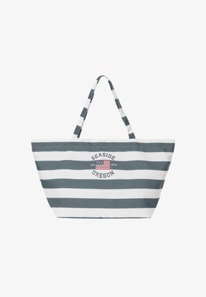 Sac fourre-tout rayé gris et blanc avec des poignées, avec un drapeau américain et le texte « Seaside Oregon » avec des coordonnées géographiques.