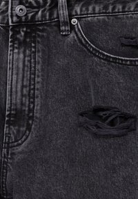 Jean en denim noir avec un design usé, comprenant une grande déchirure effilochée sur la cuisse. Comprend un bouton en métal et des coutures ton sur ton.