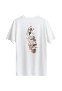 Witte katoenen T-shirt met een grafisch ontwerp van een skateboard met gedempte bruine en grijze accenten, op de achterkant. Korte mouwen, ronde hals.