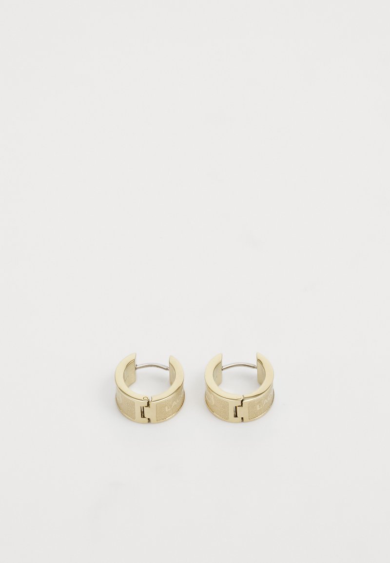 Guldörhängen i form av ringar med en strukturerad yta, utrustade med en låsmekanism och en slät, rund form. Märkbar gravyr på ytan.