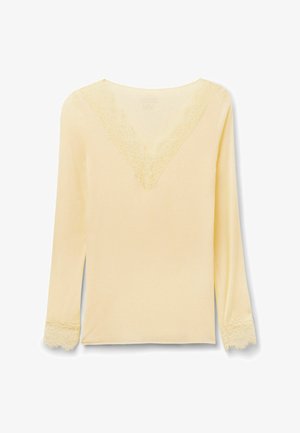 Krémová halenka s dlouhým rukávem, ozdobená krajkou na výstřihu do véčka a manžetách rukávů, jednoduchý a elegantní design.