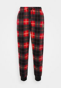 Zwarte, rode en witte geruite joggers met een elastische tailleband, koord en geribde manchetten. Het patroon heeft grote kruisende lijnen.