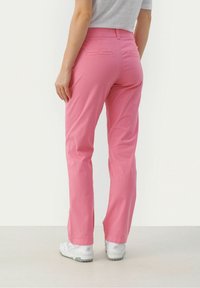 Rosa bomullsbukser med rak benform, med bakfickor och midjeband. Kombination med vita sportskor.