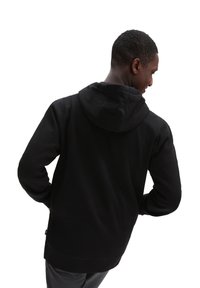 Sudadera negra con un corte relajado, fabricada en un material suave y con una gran capucha. Presenta mangas largas y un dobladillo que cae justo por debajo de la cintura.