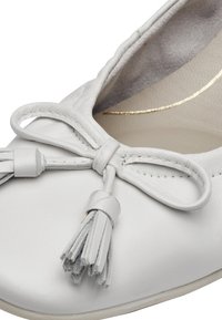 Ballerine in pelle bianca con un accento a fiocco e frange, interno morbido e una leggera lucentezza. Design con punta arrotondata.