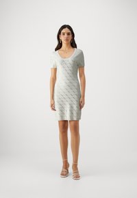 Šviesiai žalia trumparankovė, aptempta suknelė su tekstūruotu deimantų raštu. Turi apvalų iškirpimą ir kelio ilgio kirpimą. Prideda paprastumo.