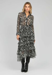 Robe à motifs noir et blanc avec un design transparent et volé ; présente un col boutonné et des manches longues. Assortie à des bottes noires jusqu'au genou.