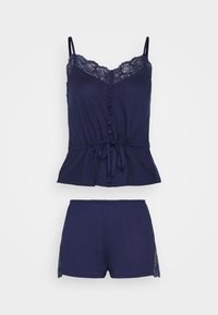 Donkerblauwe pyjama set met een cami-top met kantafwerking, knopen en een taille met trekkoord, gecombineerd met bijpassende shorts die kantaccenten aan de zijkanten hebben.