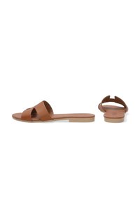 Brune lædersandal med flad sål, der har åben bag og en bred rem, der krydser foran. Tekstureret med en glat finish.