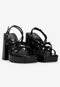 Sandalias de plataforma de charol negro con punta cuadrada, tiras anchas entrelazadas, correa en el tobillo y tacón grueso alto. Talla 36.