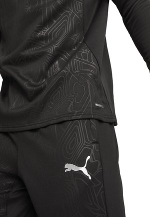 Zwarte sportkleding met een gestructureerd patroon, lange mouwen en een zilveren Puma-logo. Gemaakt van vochtafvoerende stof.