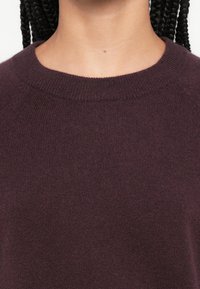 Pulover mov închis cu guler rotund striat și țesătură moale, texturată, cu un design strâns pe corp.