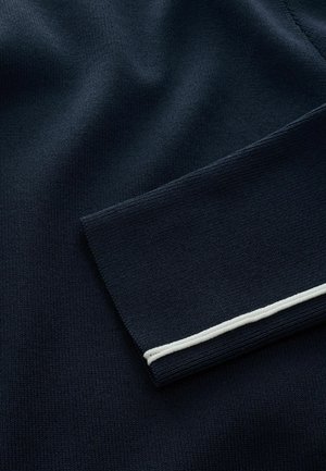 Meriharmaa neulottu kangas, jolla on sileä rakenne ja valkoinen yksityiskohta kauluksen helmassa. Ominaisuuksiin kuuluu taitettu kaulussuunnittelu.