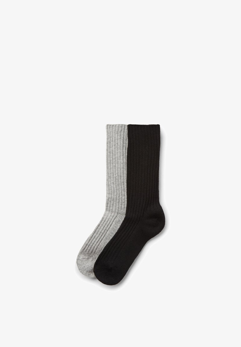 Paire de chaussettes à côtes, une entièrement noire et une entièrement grise, posées à plat et partiellement superposées sur un fond blanc.