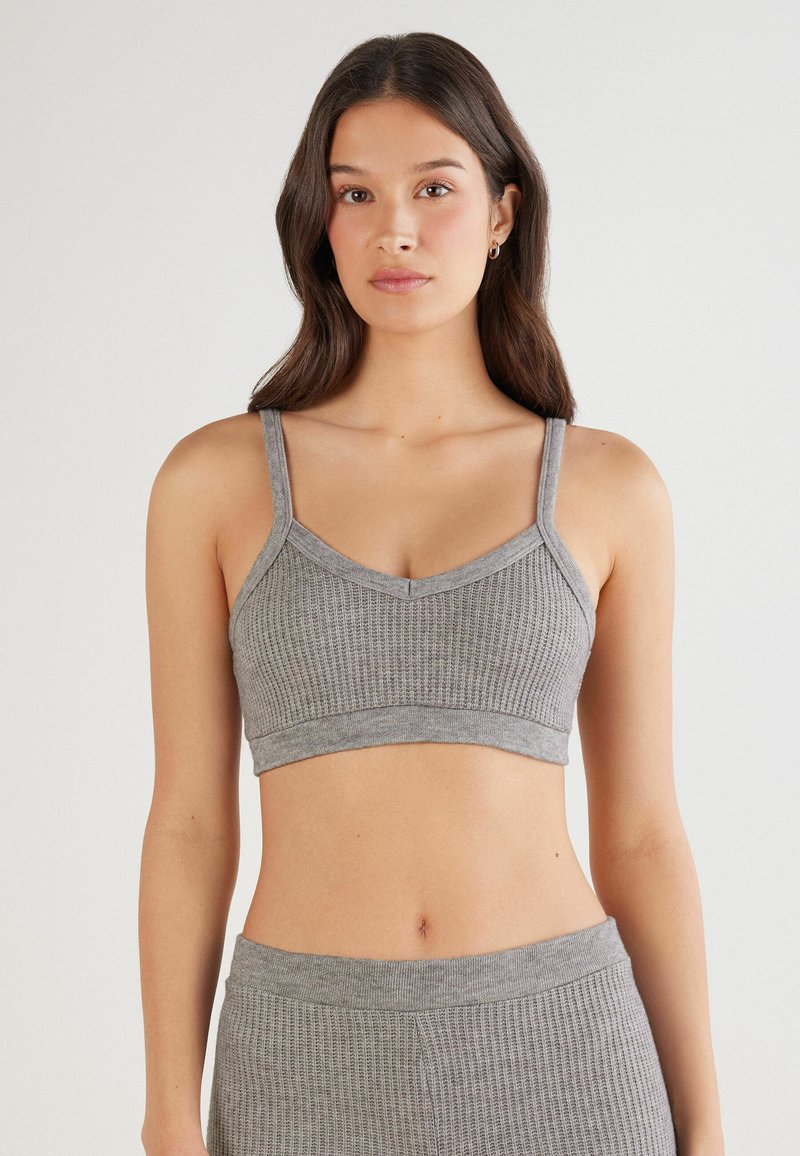 Grauer gerippter Bralette mit dünnen Trägern und V-Ausschnitt. Aus weichem Material gefertigt, mit nahtlosem Design und einem elastischen Bund am unteren Ende.